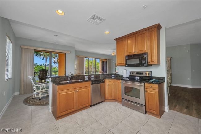 Kitchen with stainless steel appliances, a peninsula, brown cabinets, dark stone countertops, and recessed lighting | Image 15