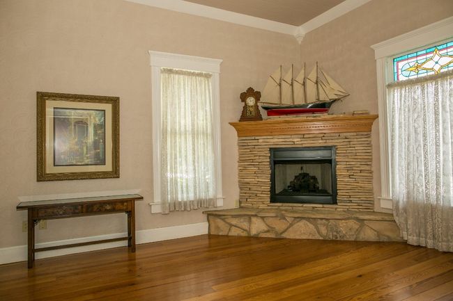 Living area with hardwood / wood-style floors, a stone fireplace, and crown molding | Image 8