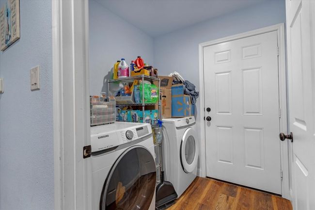Laundry area featuring washing machine and dryer and wood finished floors | Image 20