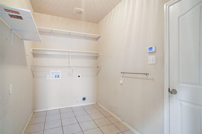 Laundry room with hookup for an electric dryer, light tile patterned floors, baseboards, laundry area, and washer hookup | Image 24