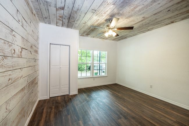 Spare room with baseboards, a ceiling fan, wood walls, dark wood-type flooring, and wooden ceiling | Image 18