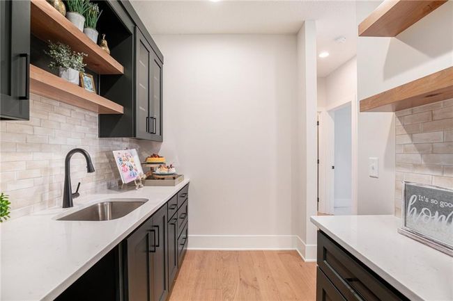 Kitchen with open shelves, light wood finished floors, backsplash, light stone counters, and recessed lighting | Image 12