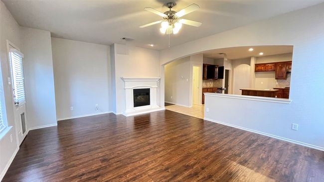 Unfurnished living room featuring ceiling fan, wood finished floors, arched walkways, a glass covered fireplace, and recessed lighting | Image 13
