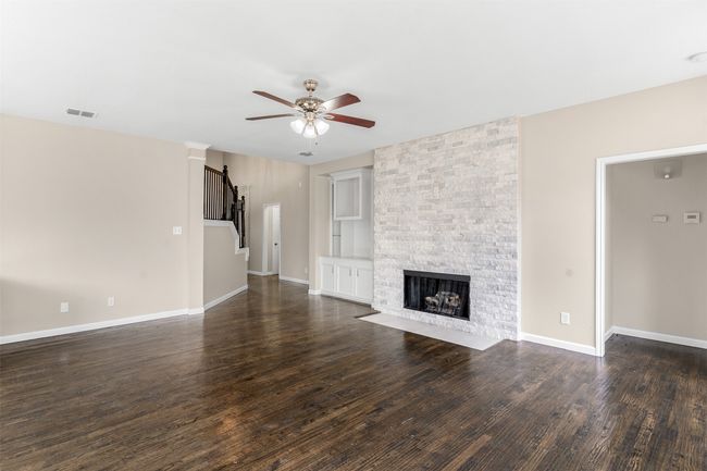 Unfurnished living room with dark wood finished floors, stairs, visible vents, and ceiling fan | Image 18