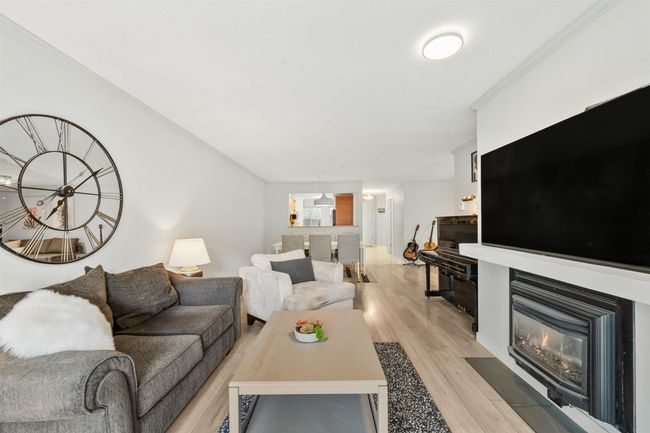 Living room with ornamental molding, light wood finished floors, and a fireplace with flush hearth | Image 5
