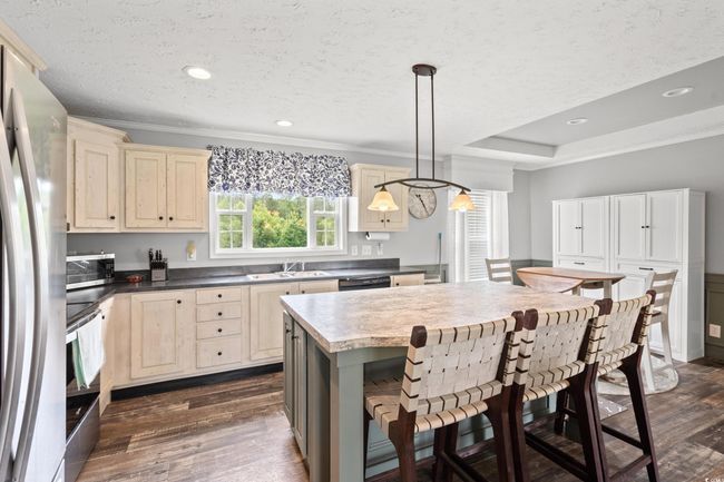 Kitchen with stainless steel appliances, cream cabinetry, dark wood-style flooring, a textured ceiling, and ornamental molding | Image 8