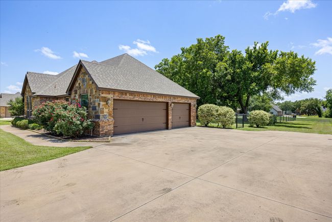 View of home's exterior featuring concrete driveway, an attached garage, stone siding, and brick siding | Image 30