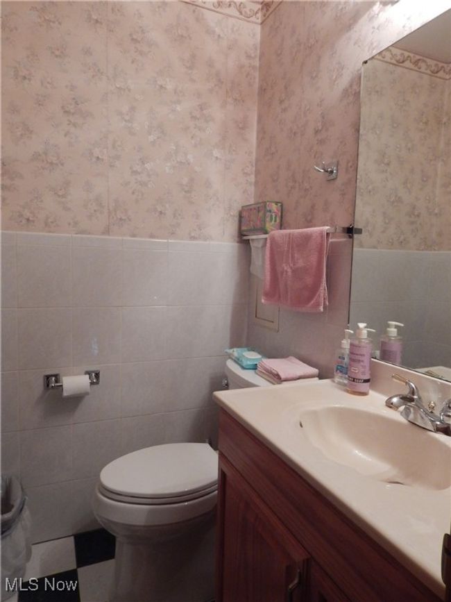 Half Bathroom featuring wainscoting, toilet, and large Vanity is conveniently located off hall at the back doorway/garage entrance | Image 15