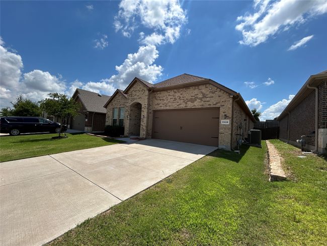 View of front facade featuring brick siding, driveway, an attached garage, and central AC | Image 4