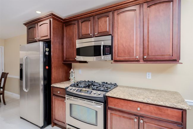 Kitchen with appliances with stainless steel finishes, light stone counters, light tile patterned flooring, and recessed lighting | Image 14