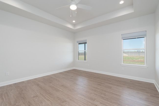 primary featuring ceiling fan, a tray ceiling, recessed lighting, wood finished floors, and baseboards | Image 20