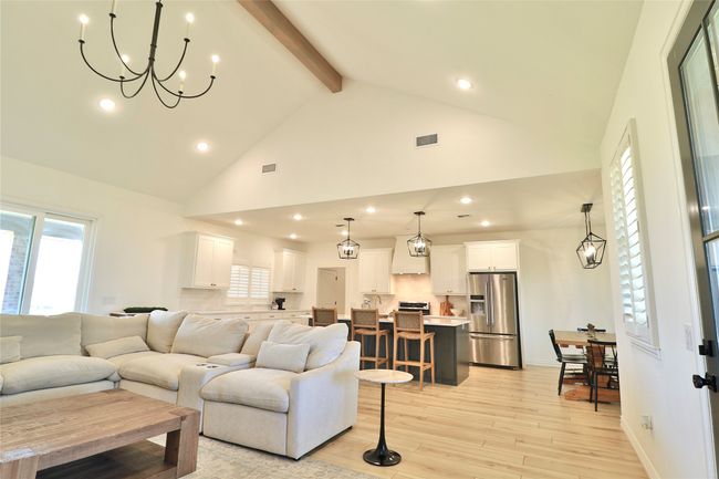 Living area featuring high vaulted ceiling, a chandelier, light wood-style floors, beam ceiling, and visible vents | Image 7