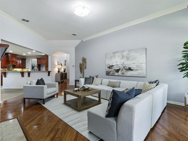Living area with arched walkways, ornamental molding, and wood finished floors | Image 16