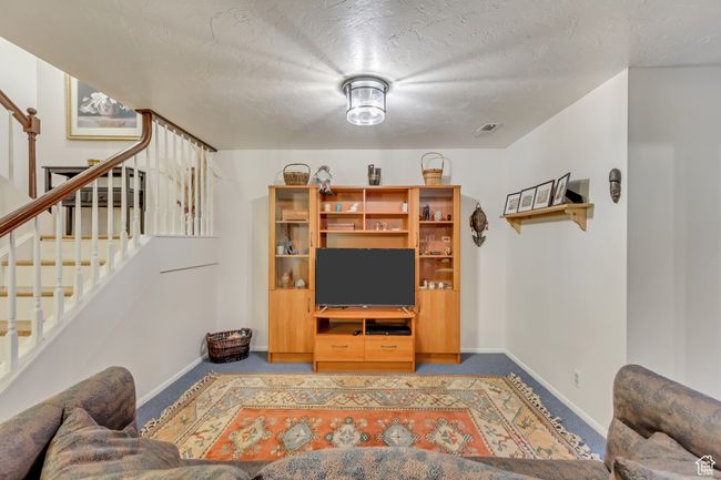 Carpeted living room featuring stairway, baseboards, and a textured ceiling | Image 24