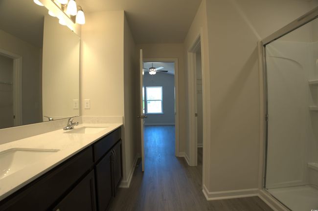 Bathroom with wood finished floors, a stall shower, a spacious closet, and double vanity | Image 12