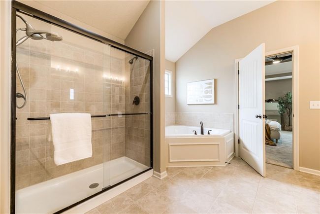 Ensuite bathroom with vaulted ceiling, a bath, a shower stall, and tile patterned floors | Image 27