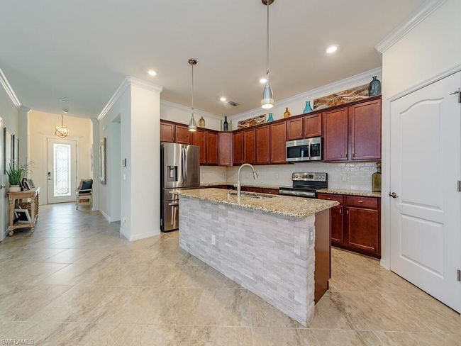 Kitchen with ornamental molding, a sink, light stone countertops, stainless steel appliances, and backsplash | Image 4