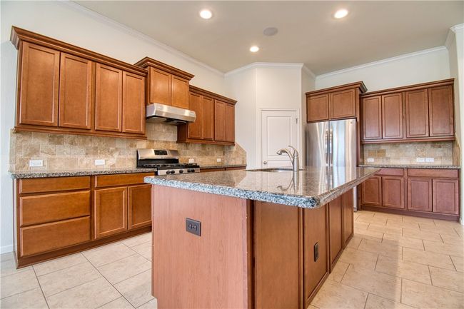Kitchen featuring a sink, stainless steel appliances, brown cabinetry, and under cabinet range hood | Image 12
