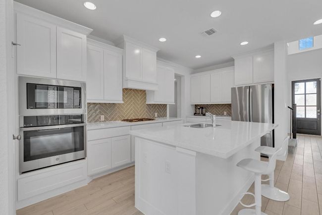 Kitchen featuring backsplash, stainless steel appliances, recessed lighting, and white cabinets | Image 9