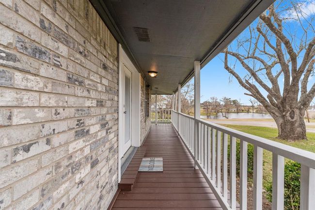 This photo showcases the welcoming front porch and offers a serene view of a large tree and a nearby pond, perfect for relaxing outdoors. | Image 7