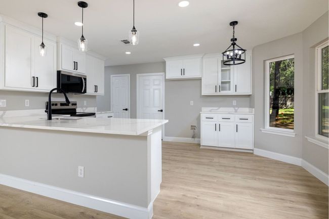 Kitchen with stainless steel microwave, electric range oven, white cabinets, a peninsula, and recessed lighting | Image 14