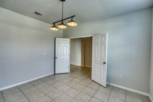 Spare room featuring light tile patterned flooring, visible vents, a textured ceiling, and baseboards | Image 8