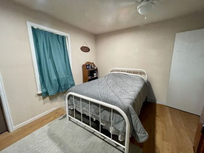 Bedroom with ceiling fan, baseboards, and wood finished floors | Image 7