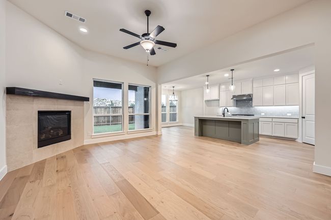 Kitchen featuring visible vents, light wood-style flooring, under cabinet range hood, white cabinetry, and open floor plan | Image 5