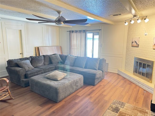 Living room with hardwood / wood-style flooring, ceiling fan, a fireplace, a textured ceiling, and beam ceiling | Image 8