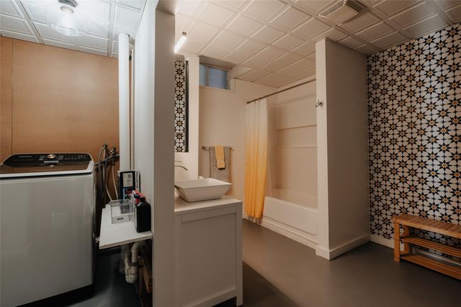 Bathroom with sink, washer / dryer, concrete floors, and shower / bath combination with curtain | Image 29