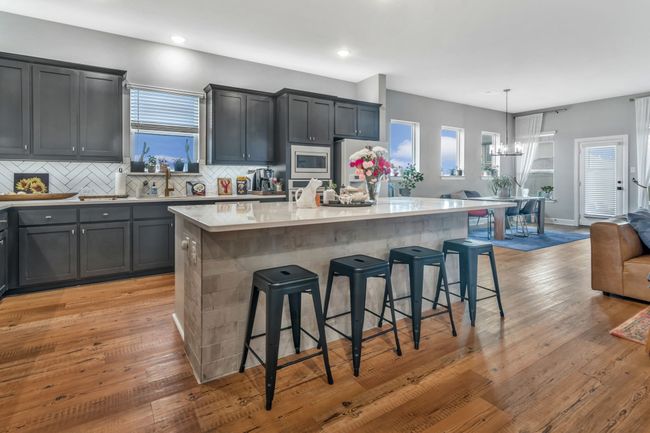 Kitchen featuring stainless steel appliances, a breakfast bar area, decorative backsplash, a center island, and light countertops | Image 7