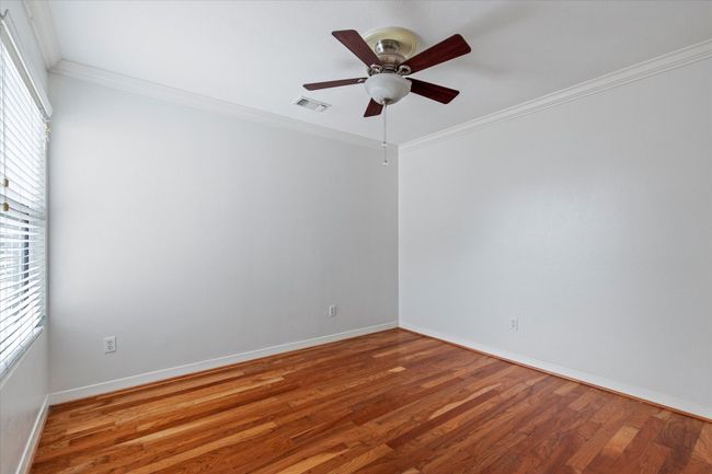 Empty room featuring healthy amount of natural light, wood finished floors, ceiling fan, baseboards, and crown molding | Image 25