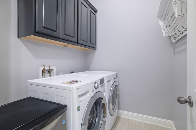 Laundry area with washer and dryer, cabinet space, baseboards, and light wood-style floors | Image 31