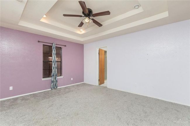 Unfurnished room featuring a raised ceiling, carpet, and ceiling fan | Image 6