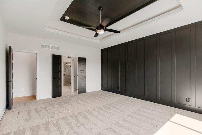 Unfurnished bedroom with a tray ceiling, light carpet, a decorative wall, and a ceiling fan | Image 19