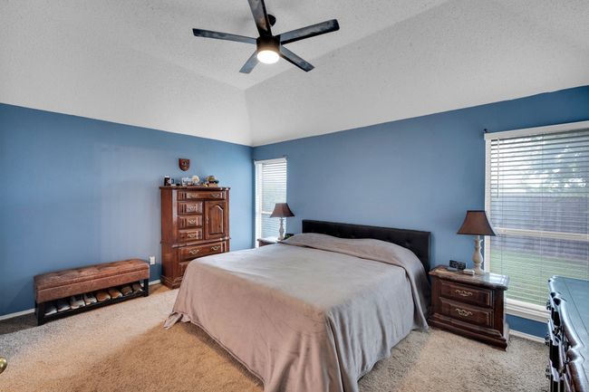 Carpeted bedroom featuring a textured ceiling, ceiling fan, and lofted ceiling | Image 25