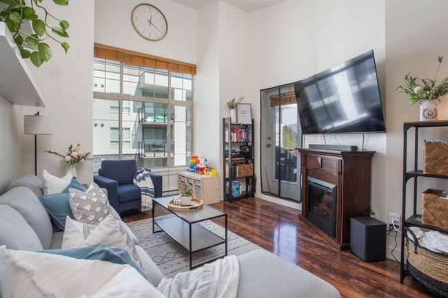 Living room featuring a glass covered fireplace, wood finished floors, and a high ceiling | Image 11