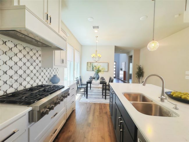 Kitchen featuring premium range hood, a sink, stainless steel gas stovetop, light countertops, and recessed lighting | Image 6