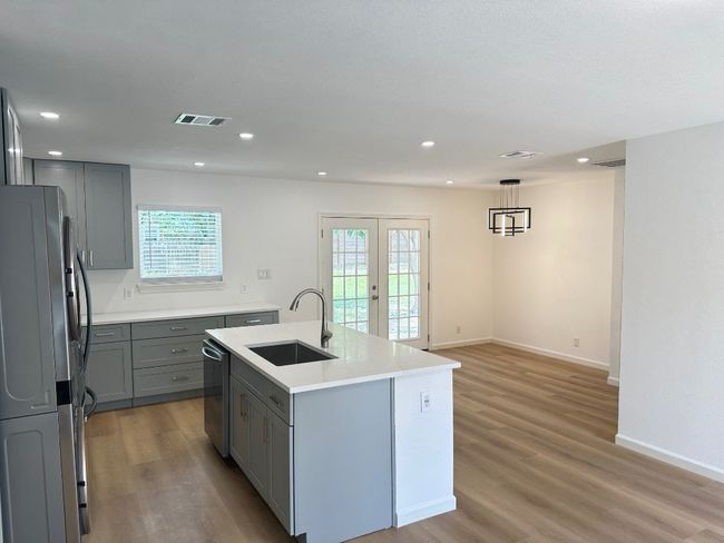 Kitchen with appliances with stainless steel finishes, a sink, gray cabinets, light wood finished floors, and recessed lighting | Image 4