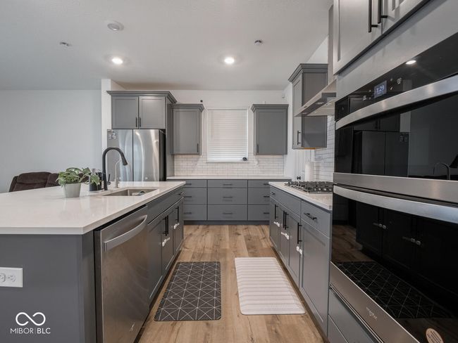 kitchen featuring gray cabinetry, tasteful backsplash, light countertops, and appliances with stainless steel finishes | Image 20