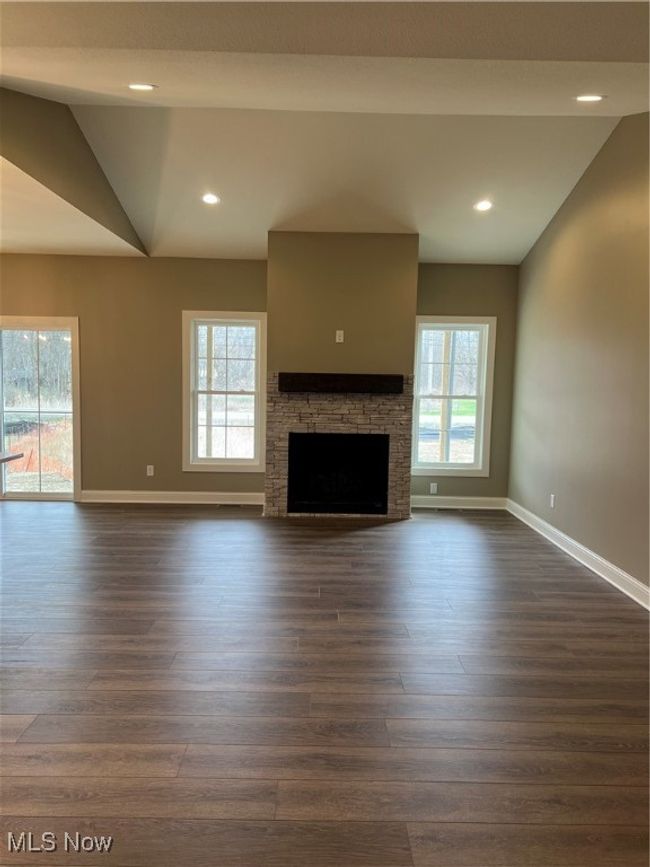 Unfurnished living room featuring dark wood-style flooring, a fireplace, recessed lighting, and lofted ceiling | Image 6
