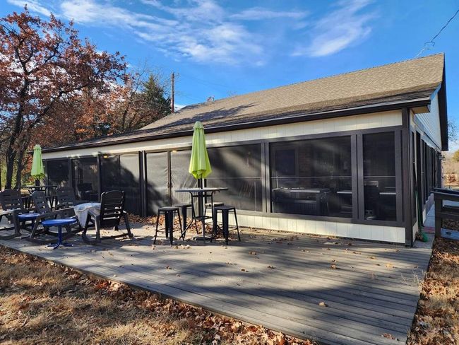 Rear view of house with a sunroom, a deck, and a shingled roof | Image 23