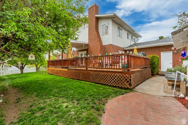 Rear view of property with brick siding, a yard, a wooden deck, and a chimney | Image 9