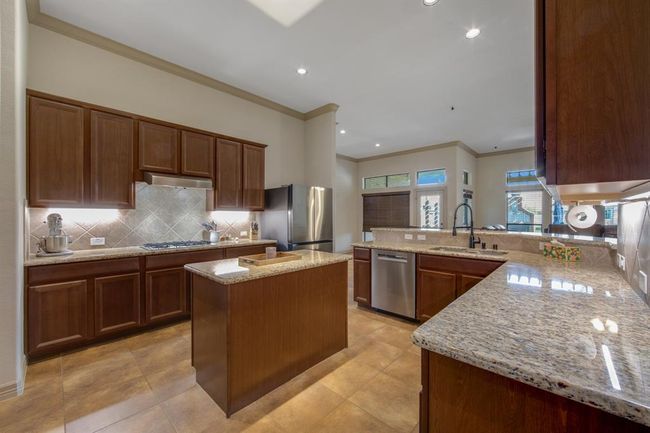 Another view of the kitchen shows the beautiful granite counters, under-cabinet lighting and the double door & double drawer stainless steel refrigerator that was purchased 11/22 that will be staying | Image 13