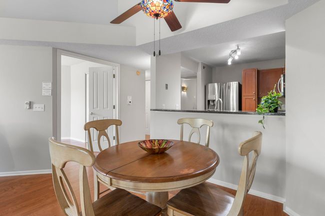 Adjacent to the kitchen, the open-concept dining and living area boasts 12-foot vaulted ceilings, tile flooring, and a unique, stylish ceiling fan. | Image 5