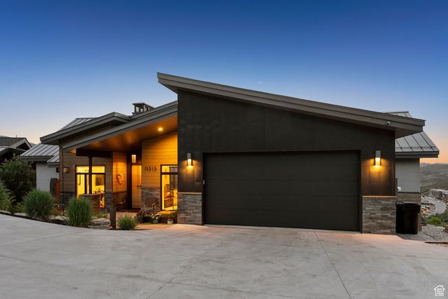 View of front of house featuring a standing seam roof, stone siding, an attached garage, and a metal roof | Image 98
