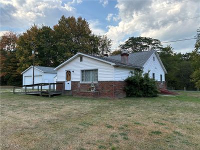 View of property exterior featuring a yard, a garage, and an outbuilding | Image 1