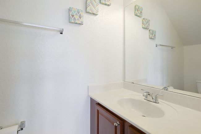 Half bathroom featuring vanity, toilet, and vaulted ceiling | Image 18
