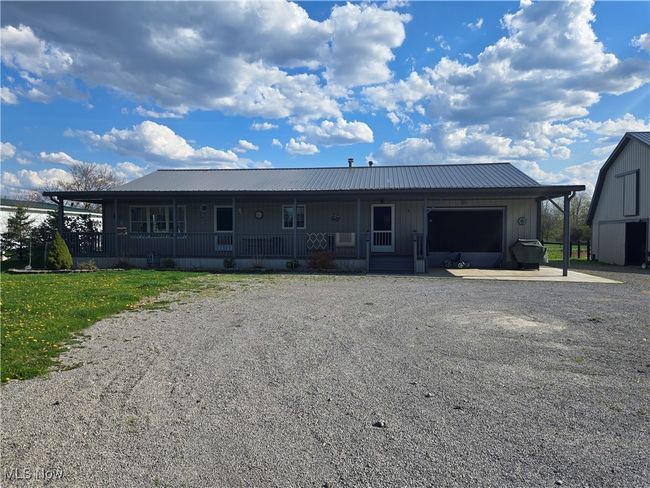 Back of house with gravel driveway, board and batten siding, metal roof, and covered porch | Image 28