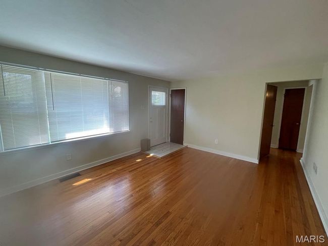 Unfurnished living room with baseboards, wood finished floors, and visible vents | Image 5